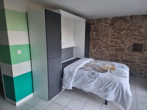 une chambre avec un lit et un mur de briques dans l'établissement L'apaisant, à Rodez