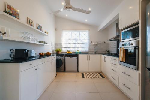 a kitchen with white cabinets and a window at Coco Beach I - Seaside Home , Pool , Beach at 200 meters in Pointe aux Cannoniers