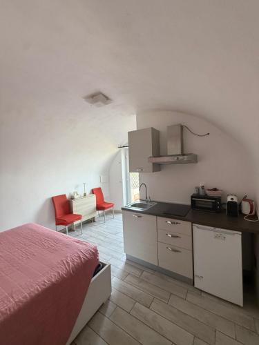 a bedroom with a bed and a kitchen with red chairs at Agriturismo Un Mare di Fiori in Ventimiglia