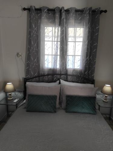 a bedroom with a large bed with two windows at Myrties House in Kalymnos