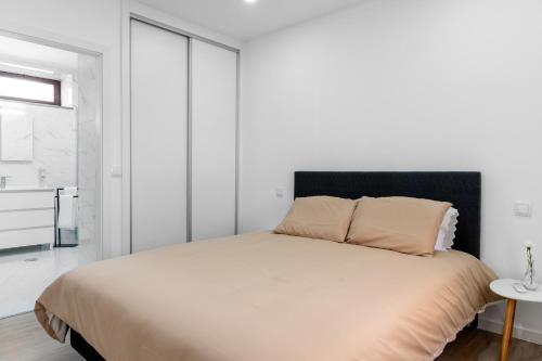 a white bedroom with a bed with a black headboard at Casinha da Avó Ana in Sever do Vouga