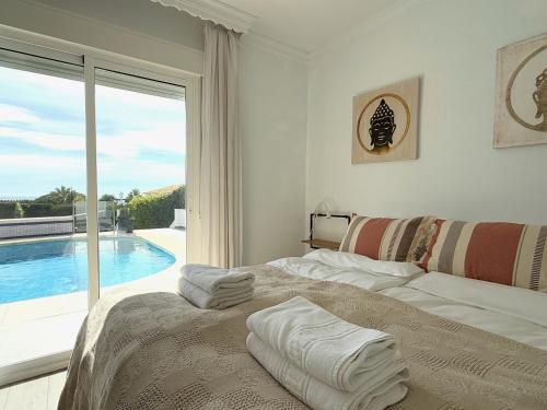 a white bedroom with a bed and a swimming pool at Villa Ibiza by Solrentspain - La Cala de Mijas in Mijas Costa