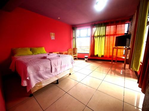 a bedroom with a bed and a red wall at Hotel Yachoon Chiin in Santiago Atitlán