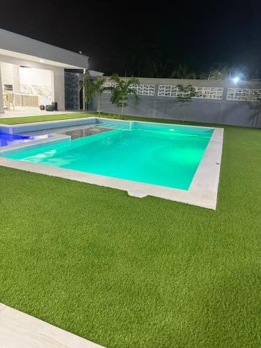 a swimming pool with green grass next to a house at Sun Beach in Puerto Colombia