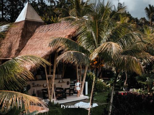 a woman standing in front of a house with palm trees at Camaya Bali - Magical Bamboo Houses in Selat