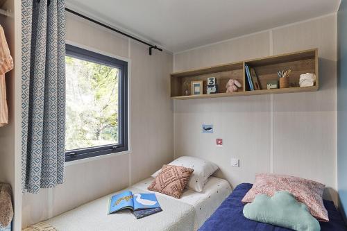 une petite chambre avec un lit et une fenêtre dans l'établissement Camping LE MOULIN DE CAUDON, à Domme