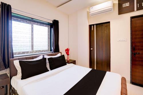 a bedroom with a bed with black and white sheets and a window at Super Hotel O Manish Nagar in Nagpur