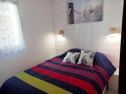 a bedroom with a colorful bed with two pillows at Appartement Arzon 4 - 5 PERSONNES , tout à pied, mer - port du crouesty - piscine in Arzon