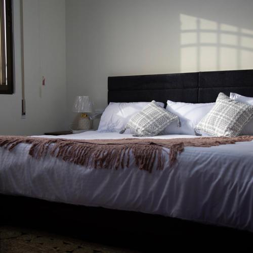 a bed with white sheets and pillows on it at LeRose Villa in Ash Shāghūr