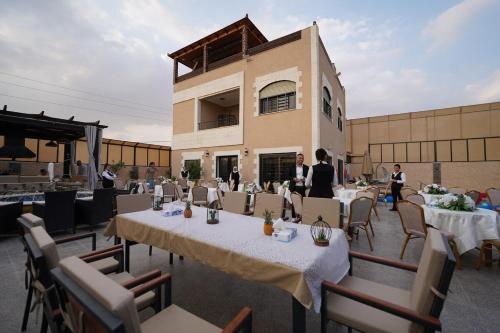 a group of people standing at tables in front of a building at LeRose Villa in Ash Shāghūr