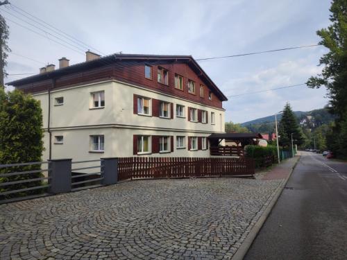 a large white building on a cobblestone street at Dom nad Wisłą - pobyty rodzinne, grupowe, terapie in Wisła