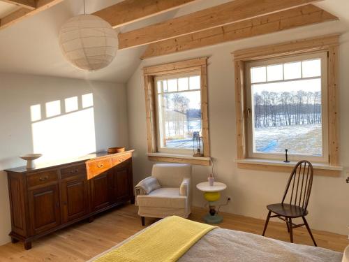 a bedroom with a bed and a chair and windows at Dom nad Buwełnem in Marcinowa Wola