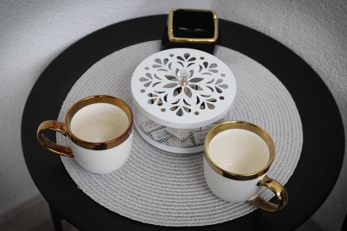 two coffee cups and a plate on a table at Apartman Aleksandra Vrnjacka Banja in Vrnjci