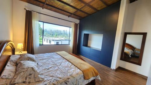 a bedroom with a large bed and a large window at La Cuadra - Hospedaje en Puembo in Puembo