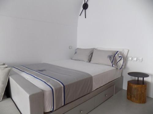 a white bedroom with a bed and a table at Imarkellis Santorini Cave House with yard in Pyrgos