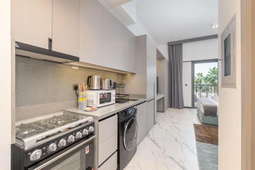 a kitchen with a stove and a microwave at Free housekeeping visits during your stay - StayShort - Modern and Stunning Studio in MAG 910 MBR City in Dubai