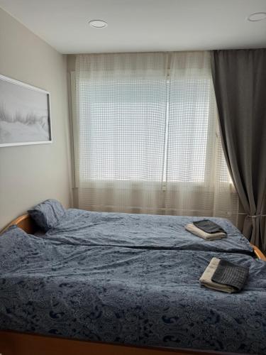a bedroom with a bed with a blue blanket and a window at Short stay in the city center, free parking in Tampere