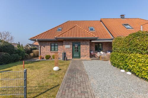 a brick house with a red roof and a pathway at Gästehaus Vier Jahreszeiten in Mildstedt