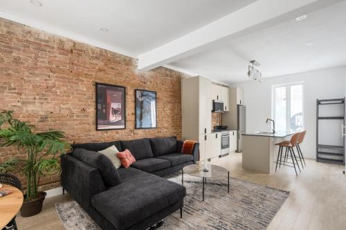 a living room with a couch and a brick wall at MTL Central Stay Apartments in Montréal