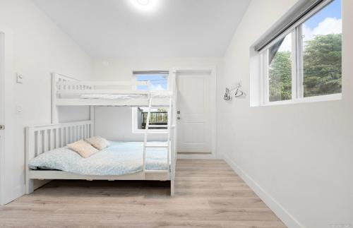 Una litera blanca en una habitación blanca con ventana. en Entire new small home, en Vancouver