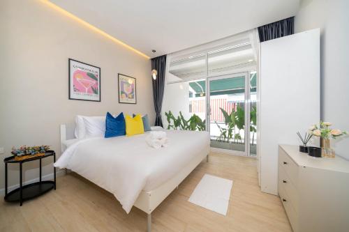 Un dormitorio con una cama blanca y una ventana grande. en Winks Beach Patong Phuket, en Patong Beach