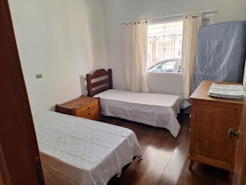 a small room with two beds and a window at Casa Assumpção, centro in Brotas
