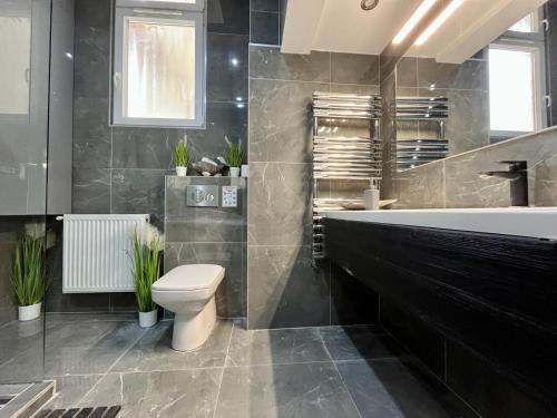 a bathroom with a tub and a toilet and a sink at JohnGold Apartment Debrecen in Debrecen