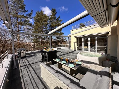 a patio with a couch and a table and a grill at Skyhouse Riga Superior Penthouse & SPA in Rīga