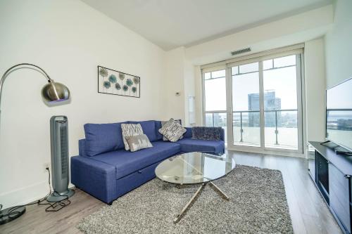 a living room with a blue couch and a glass table at RHD Luxury Condos-Downtown, CN Tower, Metro Toronto Convention Centre, Rogers Centre, Free Parking in Toronto