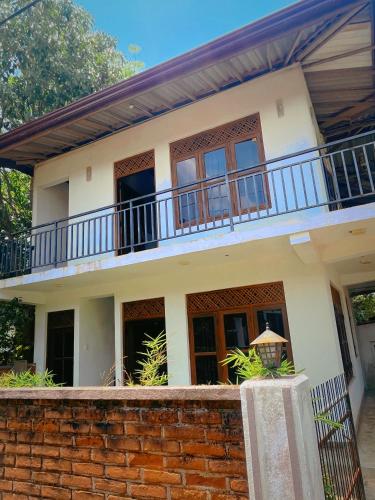 a house with a balcony on top of a brick wall at Hotel Mahagedara in Anuradhapura