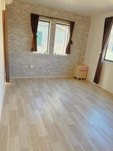an empty room with wooden floors and two windows at 呉本荘 in Kawaguchi