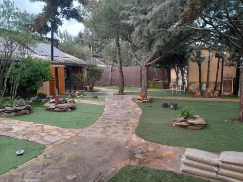 a backyard with a lawn and rocks and trees at La cabaña de Paredes in Paredes de Buitrago