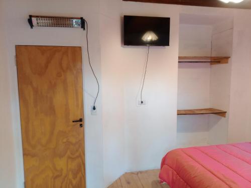 Cette chambre dispose d'une porte et d'une télévision murale. dans l'établissement CABAÑA PRIVADA NALÚ 2, Villa Ciudad Parque a 150m Río Los Reartes, à Villa Ciudad Parque