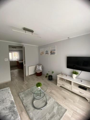 a living room with a tv and a glass table at Orzechowa Przystań in Ustka