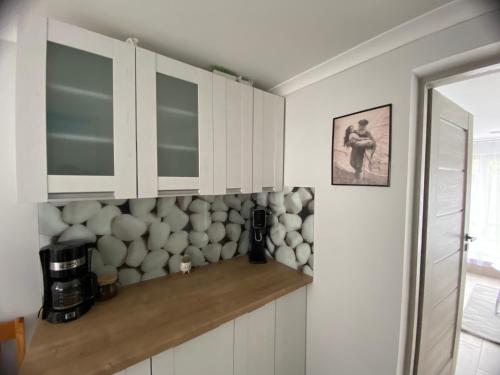 a kitchen with white cabinets and a stone wall at Orzechowa Przystań in Ustka