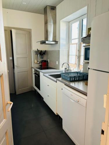a kitchen with white cabinets and a sink and a refrigerator at Maison des terroirs - Centre village - 500 m de la plage in La Couarde-sur-Mer