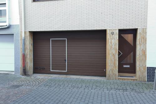 a brown garage with a door and a building at City Wohnung 12 in Brühl