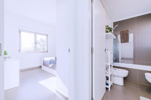a white bathroom with a toilet and a sink at Casa Coco Stylisches Beachhouse mit Pool & Sundeck Els Poblets Denia in Els Poblets