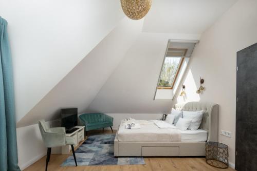 a white bedroom with a bed and a chair at Duna P'Art Panzió in Verőce
