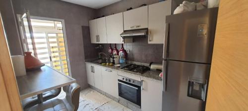 a kitchen with white cabinets and a stainless steel refrigerator at Résidence sable dor in Saidia 