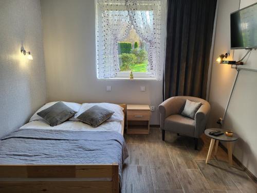 a bedroom with a bed and a chair and a window at Agroturystyka Nad strumykiem in Leśna