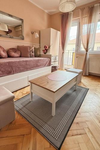 a living room with a coffee table and a bed at Middle of the city apartman 2 in Pécs