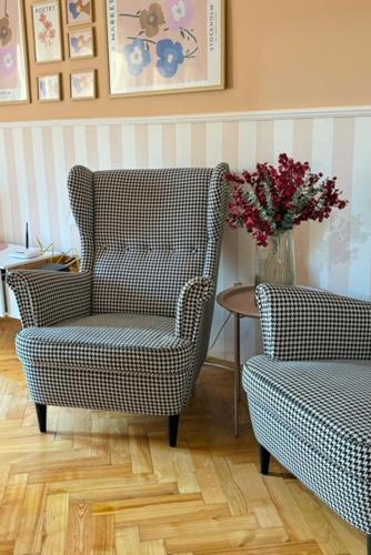 a living room with two chairs and a table with a vase of flowers at Middle of the city apartman 2 in Pécs