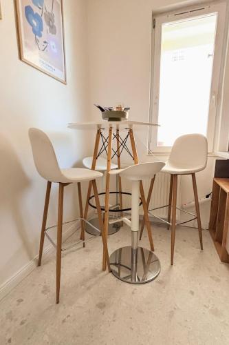 a table and three chairs in a room at Middle of the city apartman 2 in Pécs
