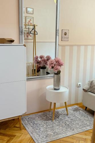 a room with a table and a vase of flowers on a table at Middle of the city apartman 2 in Pécs