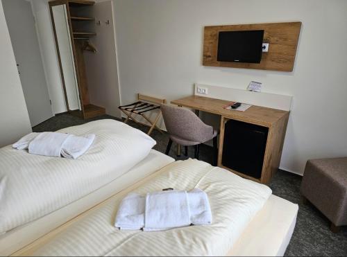 two beds in a room with a desk and a television at Gasthof goldener Engel in Kemnath