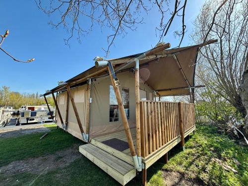 a tent with a porch on the grass at Luxe glamping tenten aan het water in Wommels