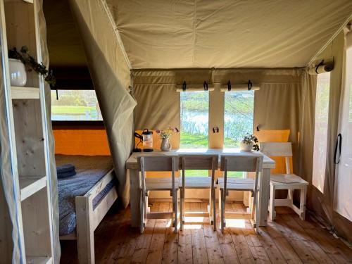 a dining room in a tent with a table and chairs at Luxe glamping tenten aan het water in Wommels