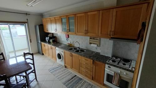 a kitchen with wooden cabinets and a sink and a stove at Quinta da Casinha Homestay in Pombal
