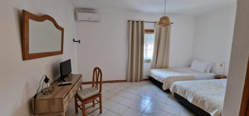 a room with two beds and a desk with a television at On The Route in Pedrógão Pequeno